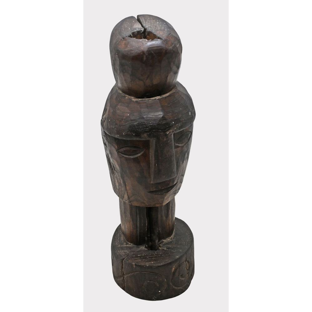 Dark aged wooden tribal face statue, angled view