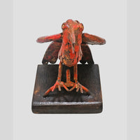 Close-up of metalwork on red antique bird figurine