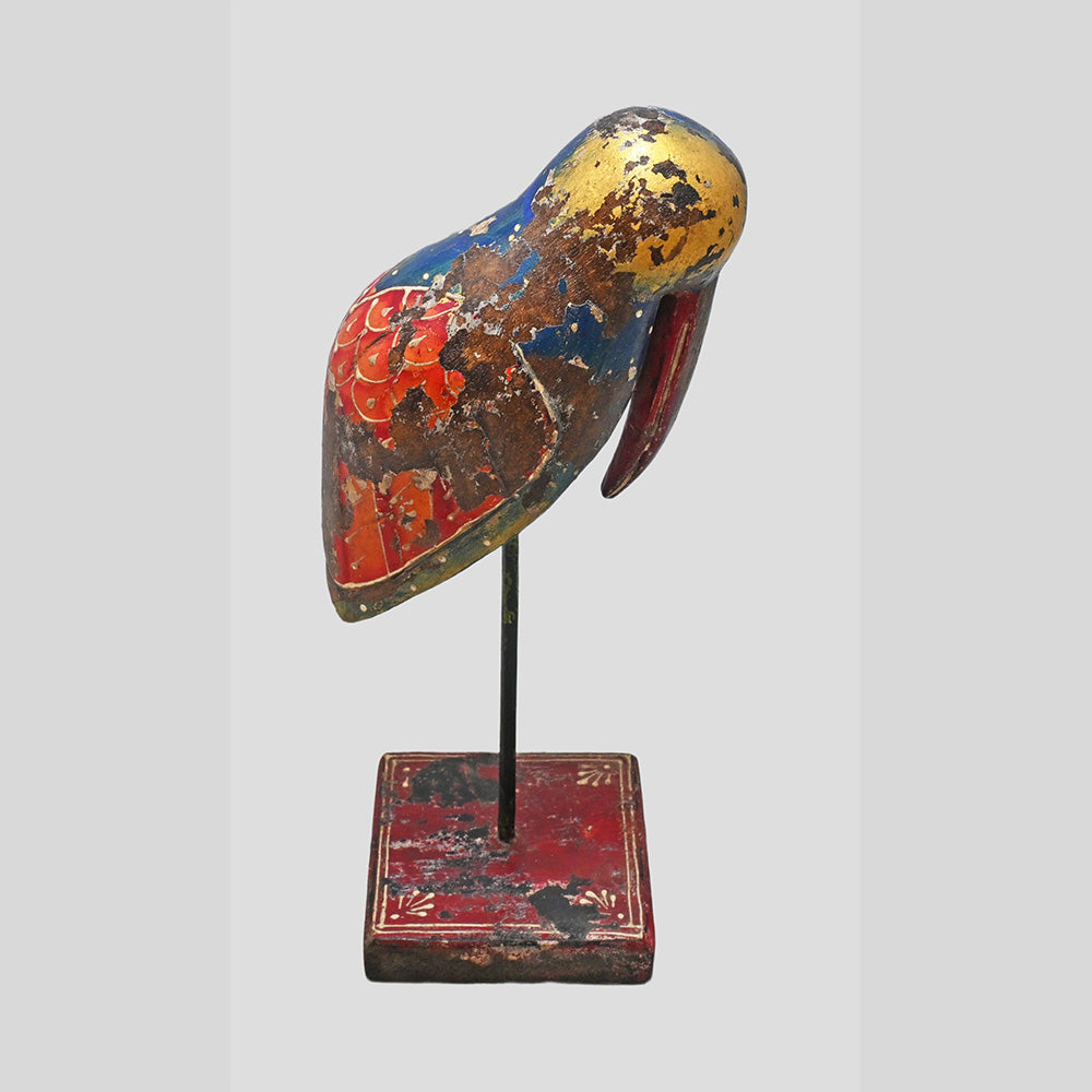 Angled view of colorful wooden bird sculpture on decorative stand