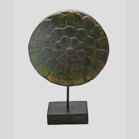 Angled view of carved wooden medallion with aged green finish