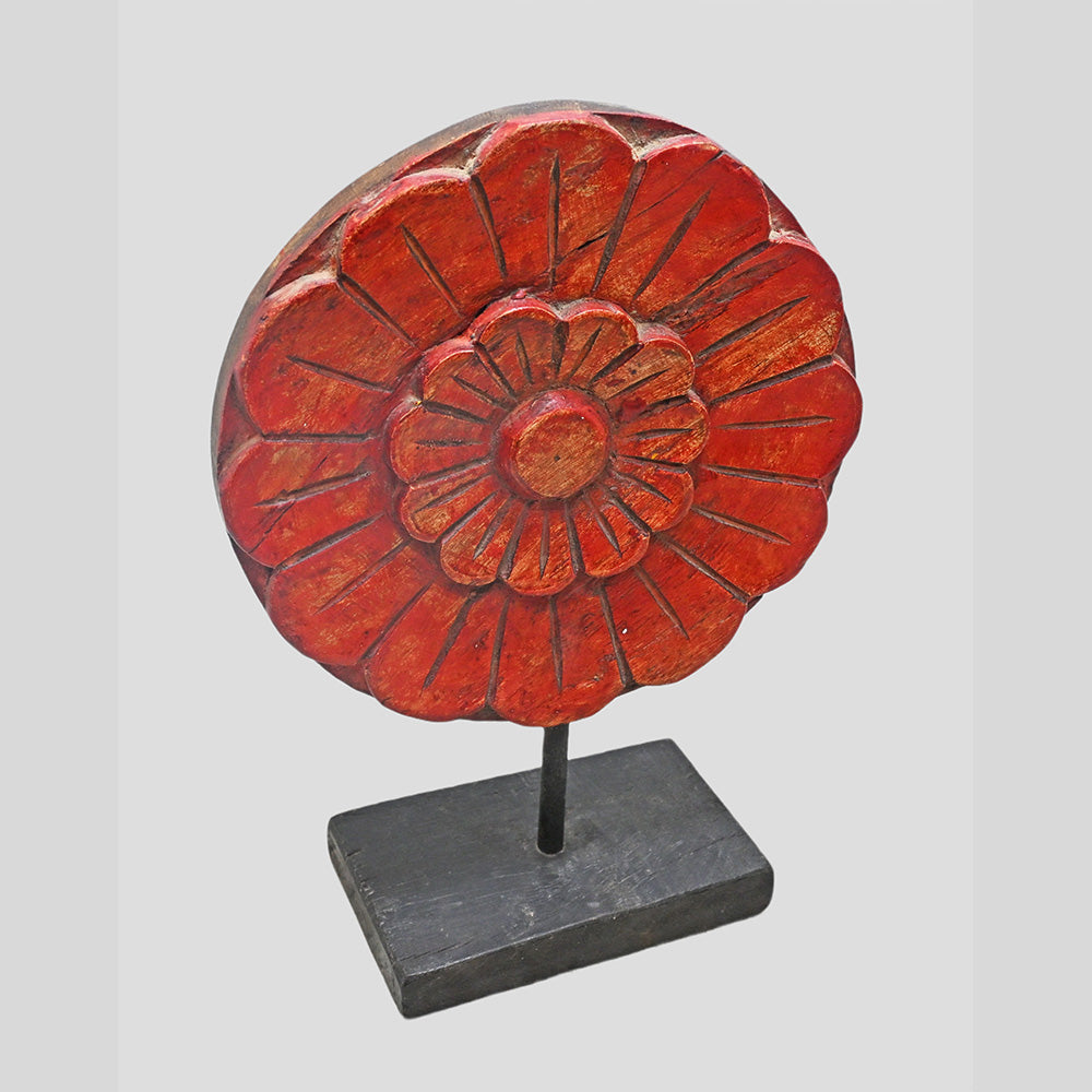 Angled view of round carved wooden floral medallion in red finish