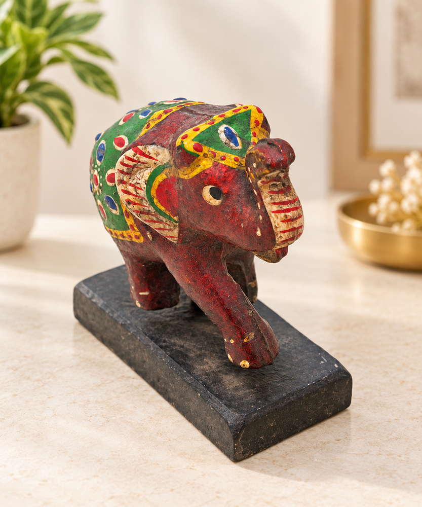 Hand-painted wooden elephant figurine with colorful folk art patterns on base, front view