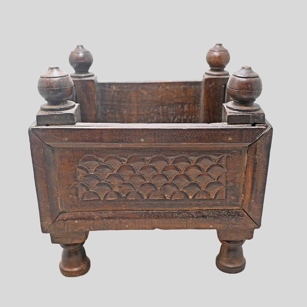 Side view of wooden storage box with raised legs and finials