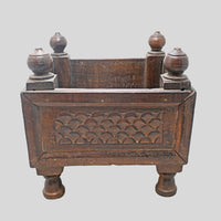 Side view of wooden storage box with raised legs and finials
