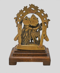 Brass Radha Krishna statue showing wooden Bajot display base
