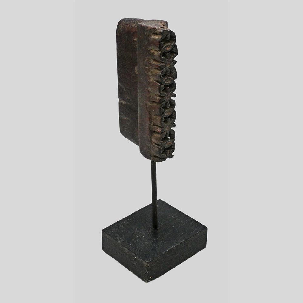 Angled view of dark brown carved wooden printing block