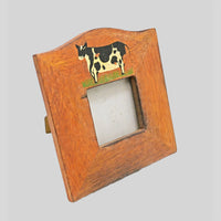 Wooden photo frame with painted cow motif, angled view