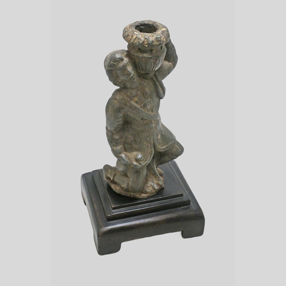 Antique cast metal man figurine carrying a pot, decorative candle holder, angled view
