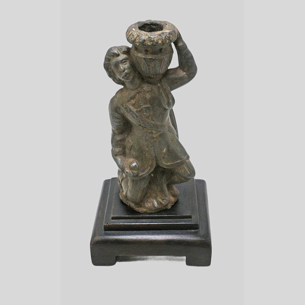 Antique cast metal man figurine carrying a pot, decorative candle holder, close-up detail