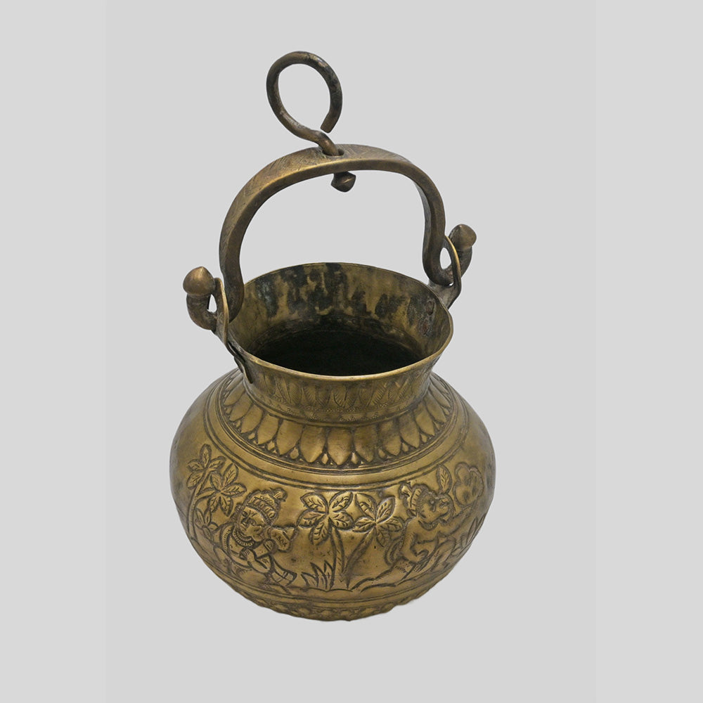 Antique brass holy water pot with engraved floral and traditional figures, angled view
