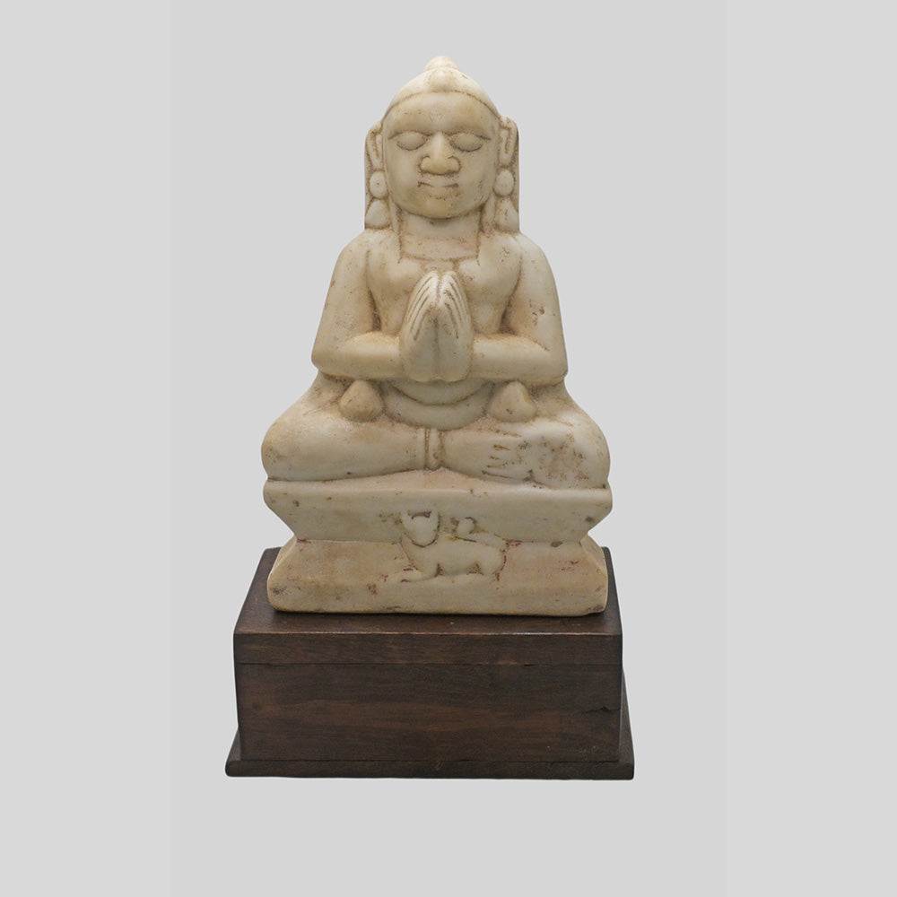 Hand-carved seated Jain Lord Mahavira statue on wooden display base, close-up detail