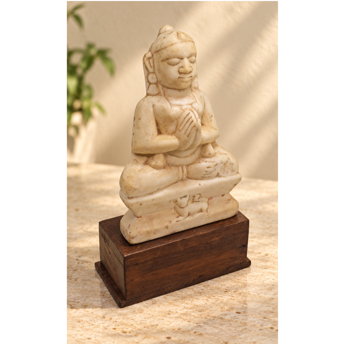 Hand-carved seated Jain Lord Mahavira statue on wooden display base, front view